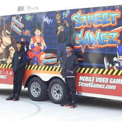 Two men standing in front of a mobile video game truck.