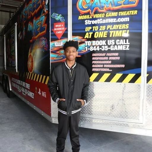 A young man standing in front of a large truck.