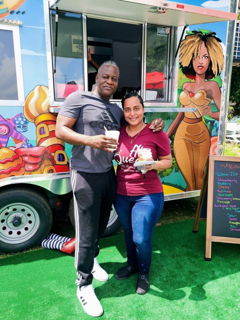 A man and woman standing in front of a food truck.